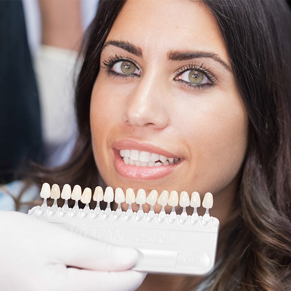 Woman's smile compared with veneers color chart