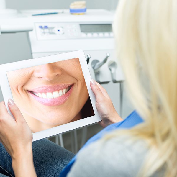 Woman looking at virtual smile design on tablet computer