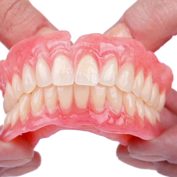 Person holding full denture from a dentist in Hingham