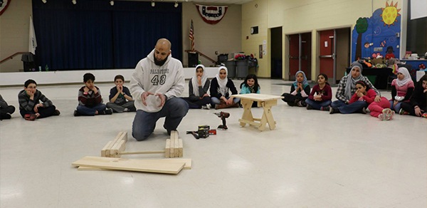 Doctor Hegazi showing group of children how to do woodworking