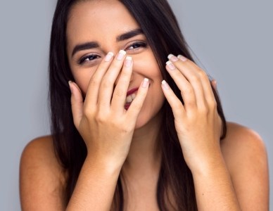 Woman with lost filling hiding her smile