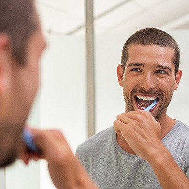 man brushing his teeth in front of a bathroom mirror 