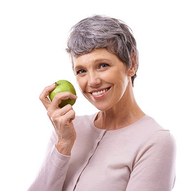 senior woman smiling and holding a green apple 