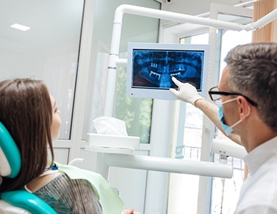 Dentist and patient looking at X-rays and discussing the cost of dental implants in Hingham