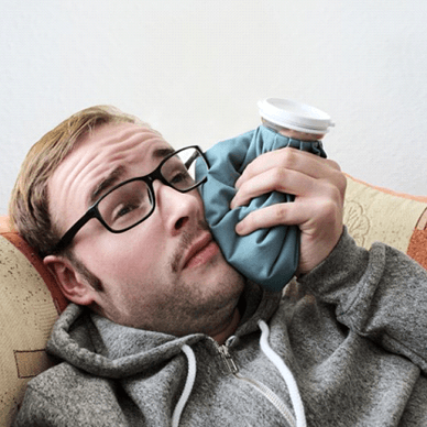 man holding a cold compress to his cheek