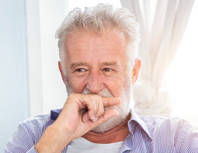 Man missing all teeth covering his smile