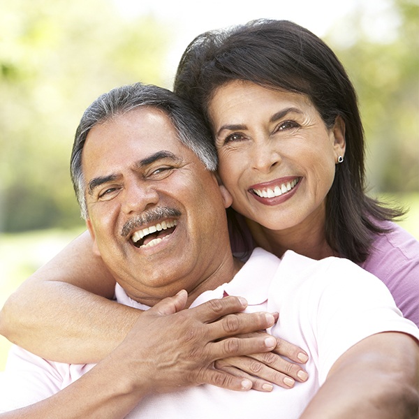 Older man and woman with healthy smiles thanks to dental bridges