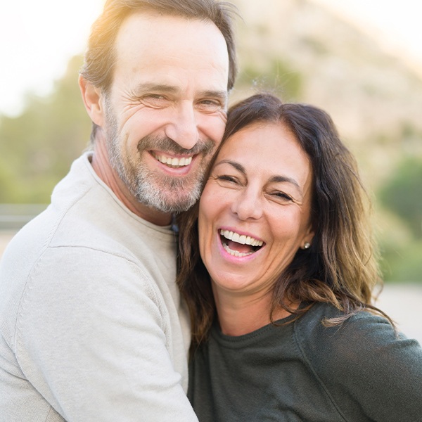 Man and woman smiling after tooth replacement with dental implants