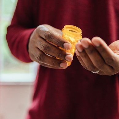 Man in red shirt holding pill bottle and pouring some into his hand