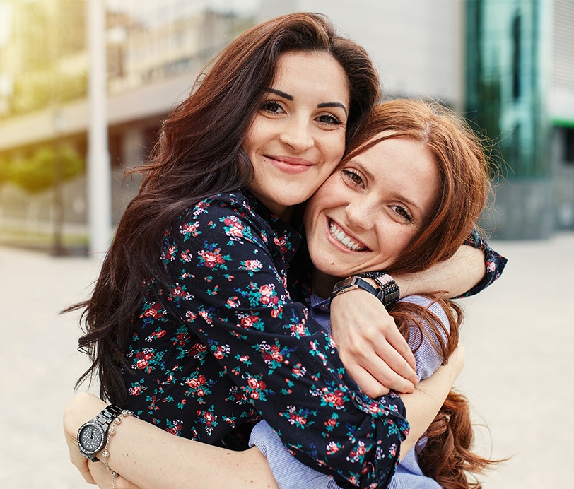 Two women with aligned smiles thanks to Invisalign