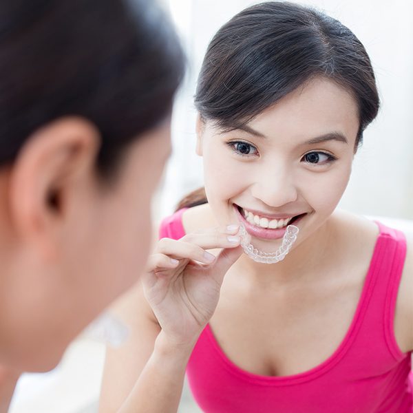 Woman placing her Invisalign tray