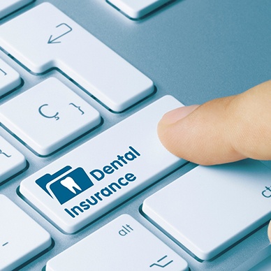 Finger pressing ‘dental insurance’ button on keyboard