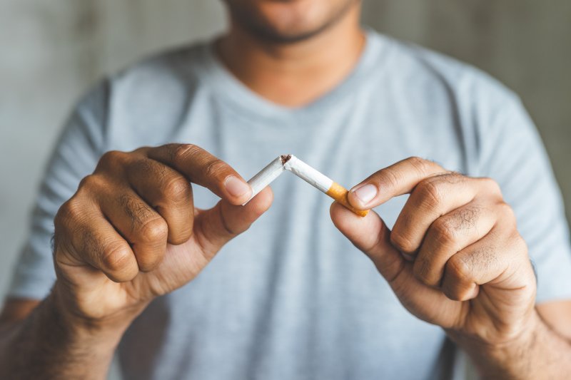 man breaking cigarette in half