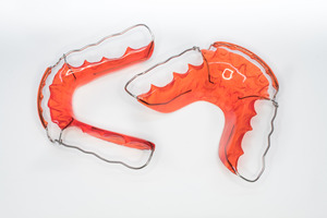 Two orange retainers sitting on a white surface